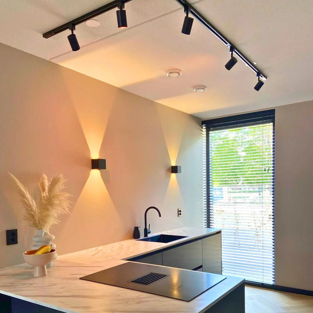 Plafondrailverlichting met zwarte spots boven keuken, spots in warm licht