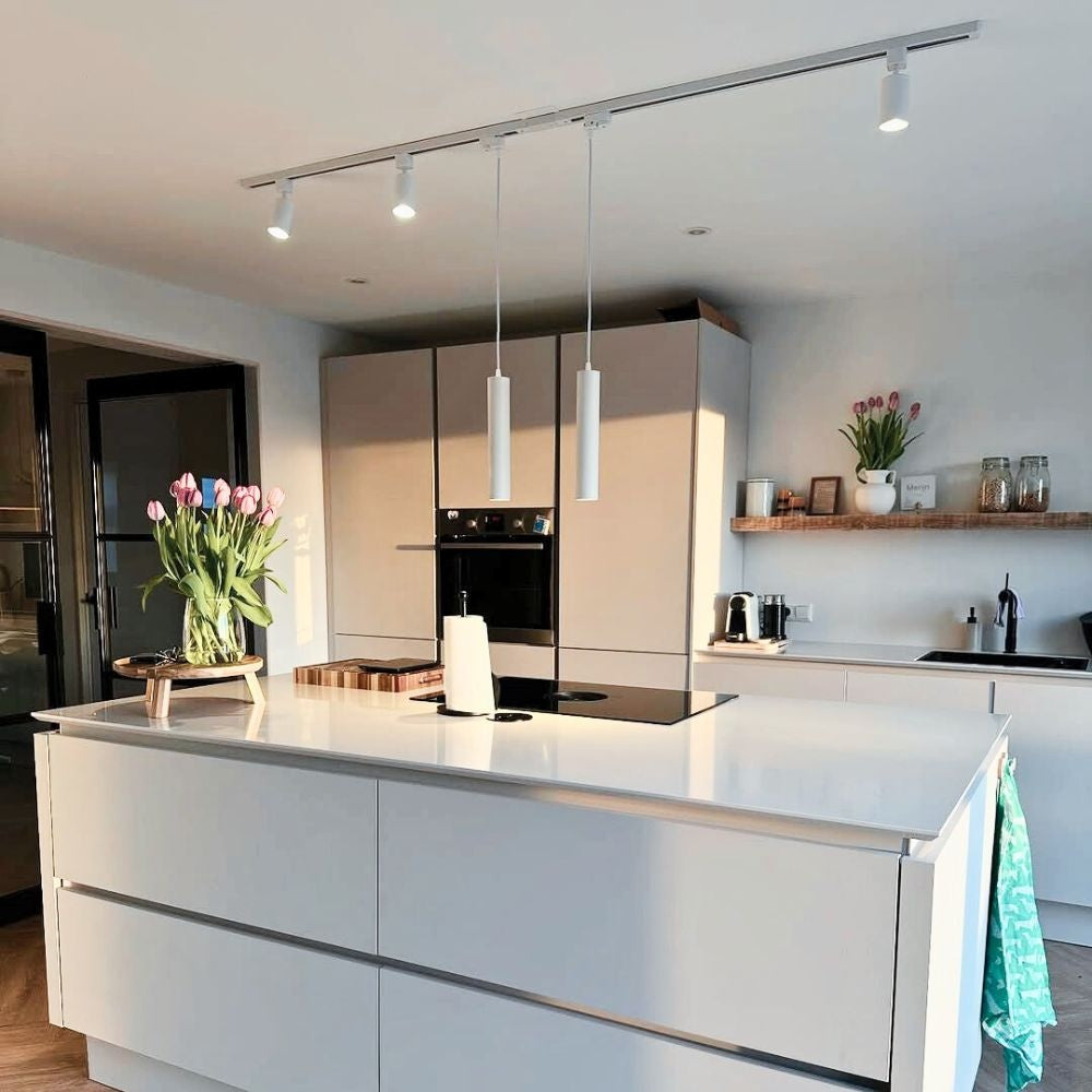 Witte railverlichting aan het plafond met 3 spots en 2 hangpendels boven keuken.